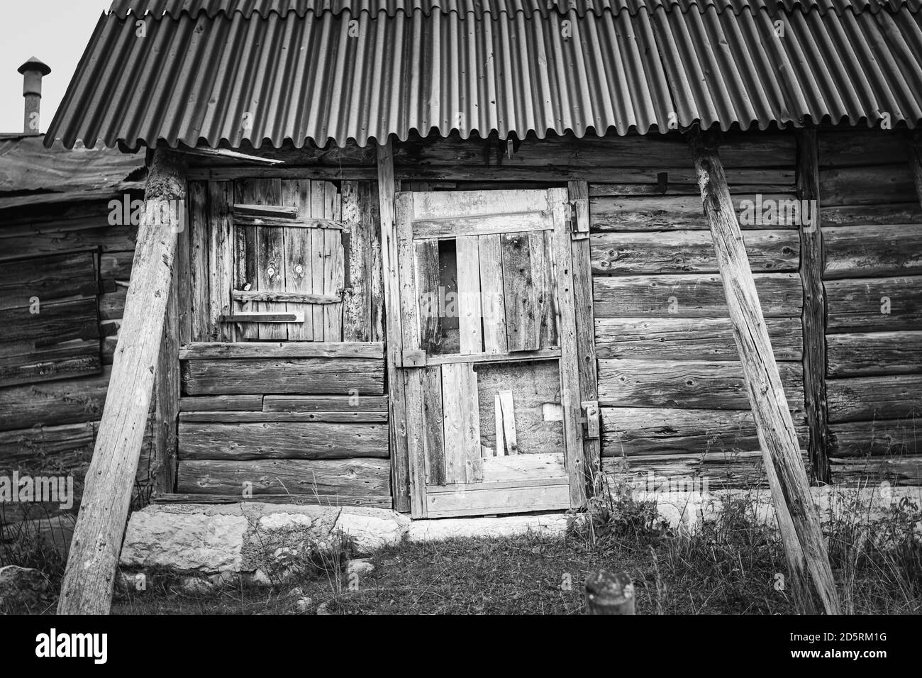 Black and white facade of old and dilapidated wooden and metal shack in the mountains of the Asiago plateau. Enego, Vicenza, Italy Stock Photo