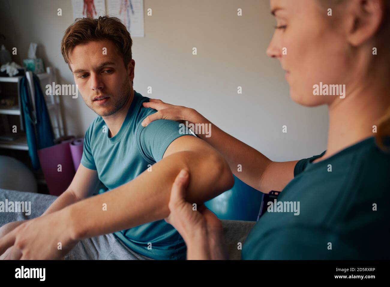 Young man undergoing physiotherapy treatment for hand injury with woman doctor Stock Photo