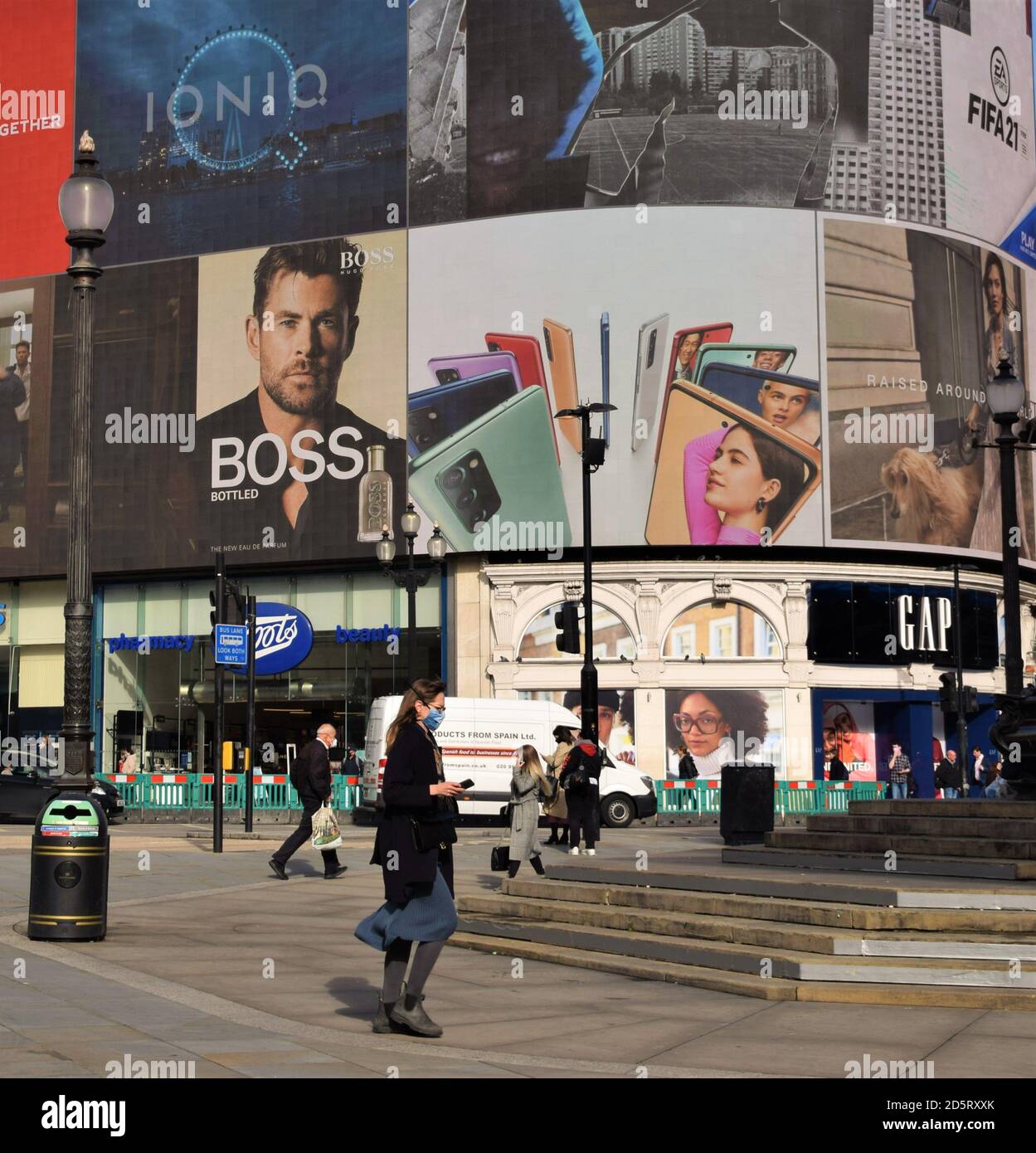 Daytime view of Piccadilly Circus with people wearing protective face