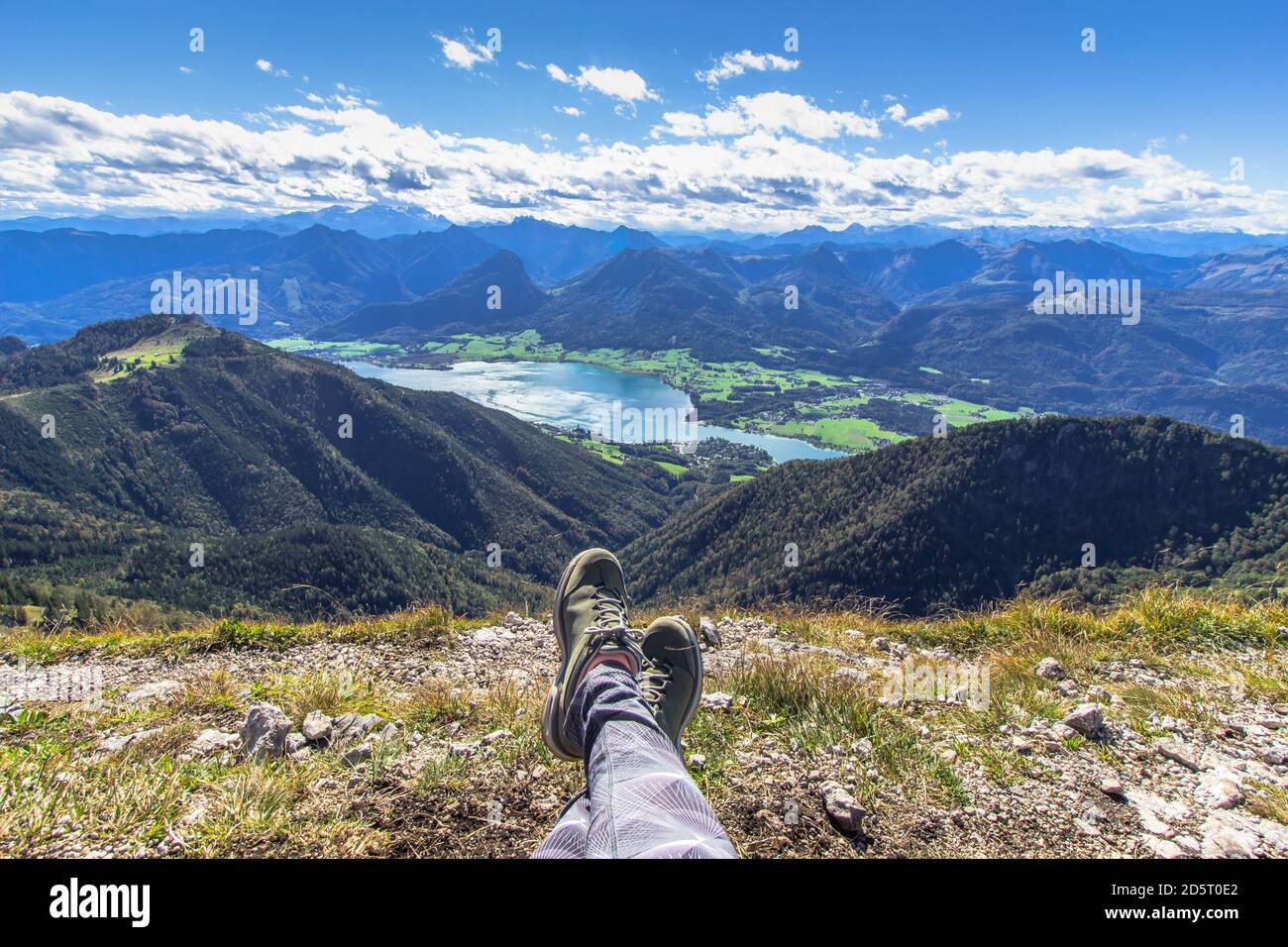 Legs of traveler sitting on a high mountain. Freedom wanderlust travel concept. Trekking boots against a beautiful landscape. Wonderful breathtaking m Stock Photo