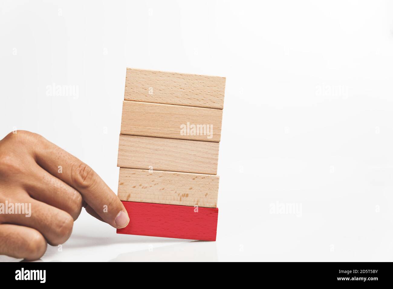Closeup shot of a human hand holding a red wooden block on the stack of ...