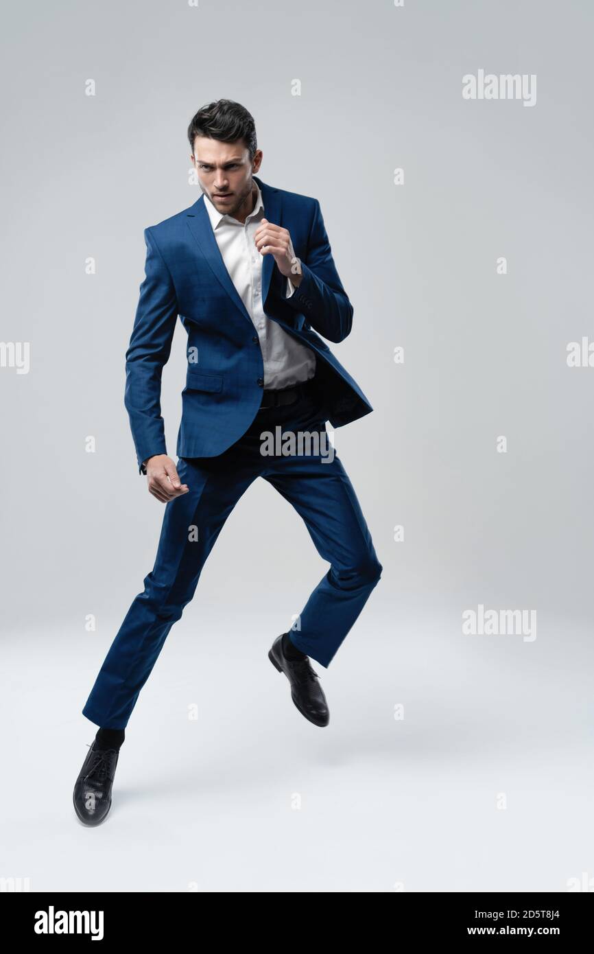 Full-length photo of funny man in suit running or jumping in air isolated  over gray background Stock Photo - Alamy