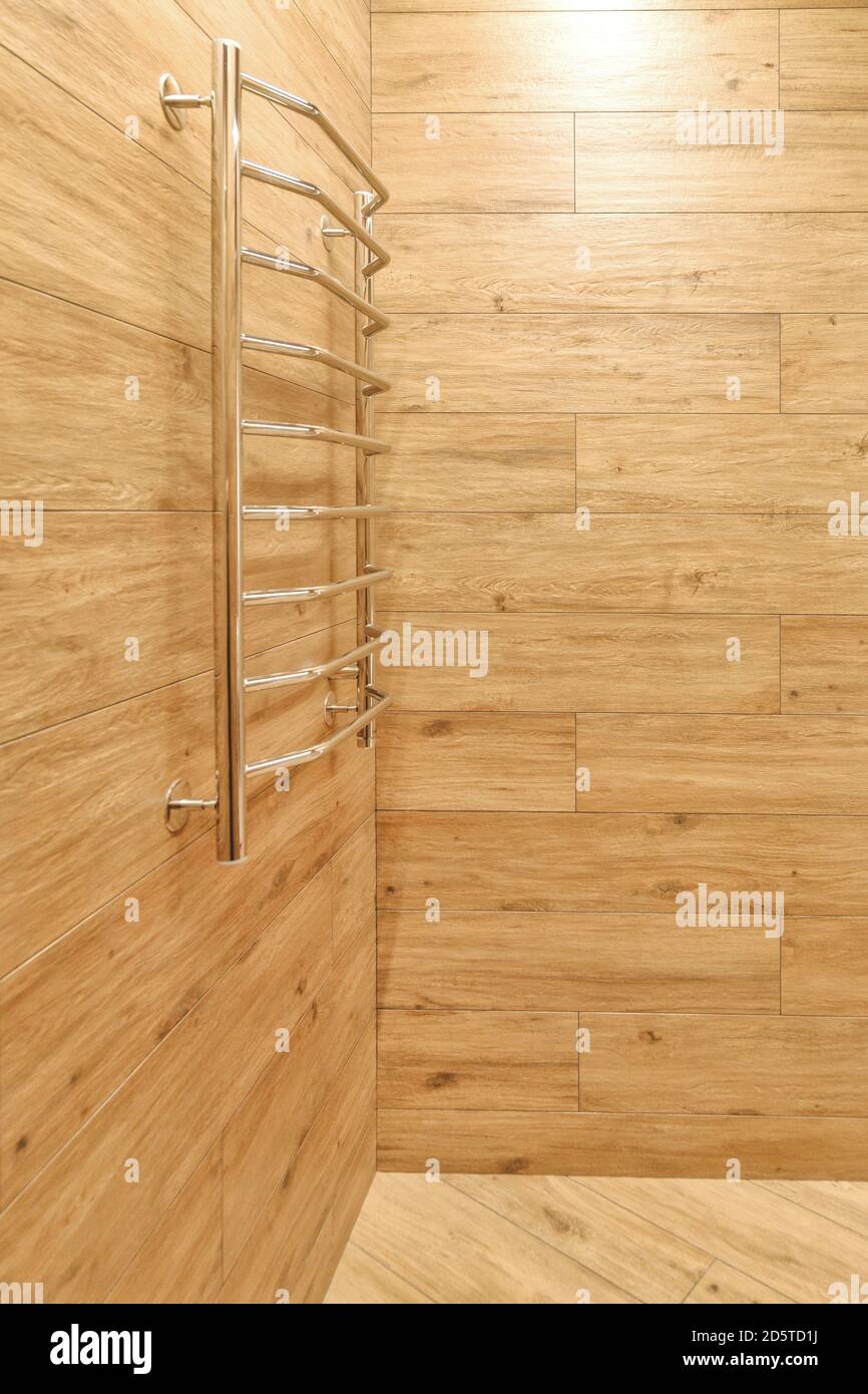steel heated towel rail in the bathroom in warm brown tones with wood