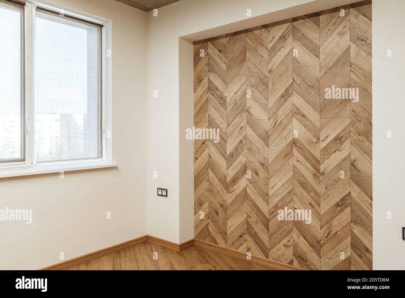 part of living room in warm colors with a finishing wall imitating wooden parquet near the white wall with a window Stock Photo