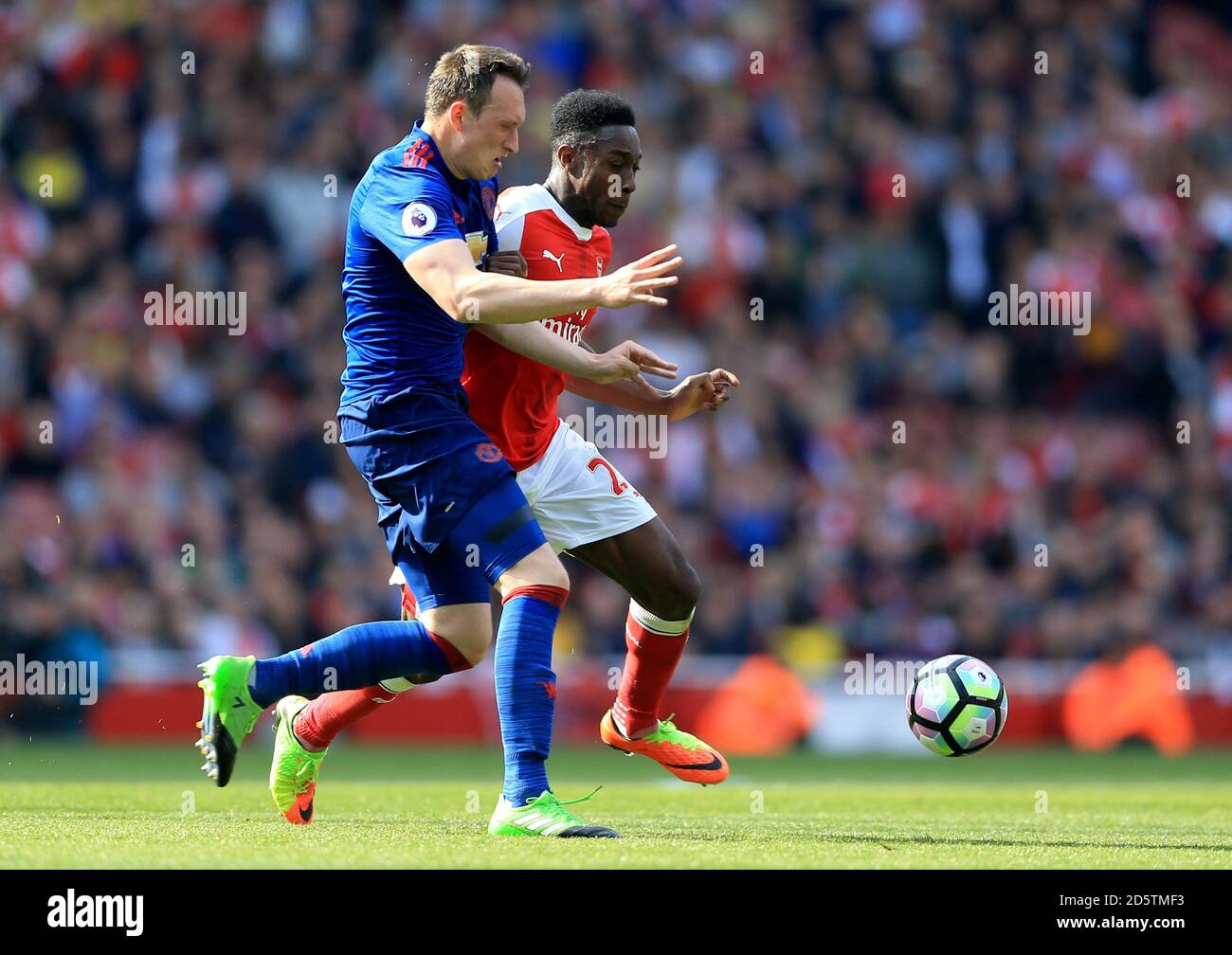 Manchester United's Phil Jones (left) and Arsenal's Danny Welbeck battle for the ball Stock Photo