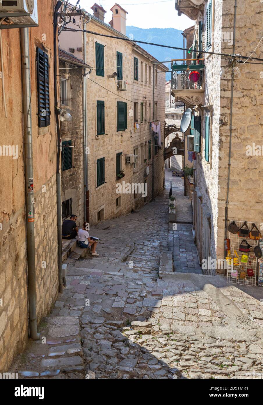 Two tourists resting in narrow cobbled street in Kotor, Montenegro Stock Photo