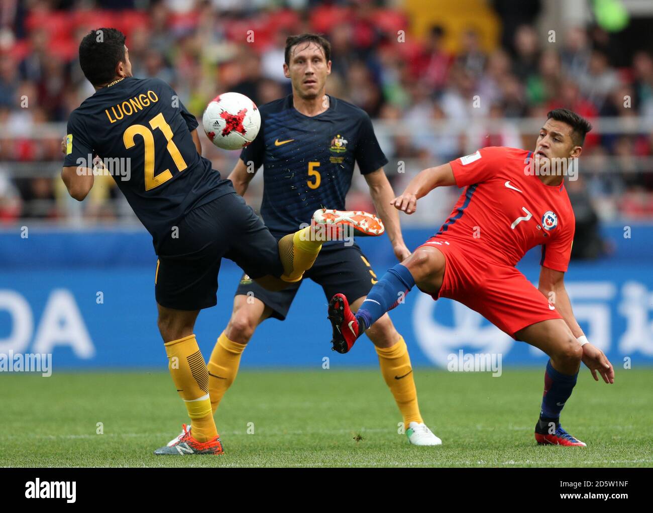 (left-right) Australia's Massimo Luongo and Mark Milligan, and Chile's Alexis Sanchez battle for the ball Stock Photo