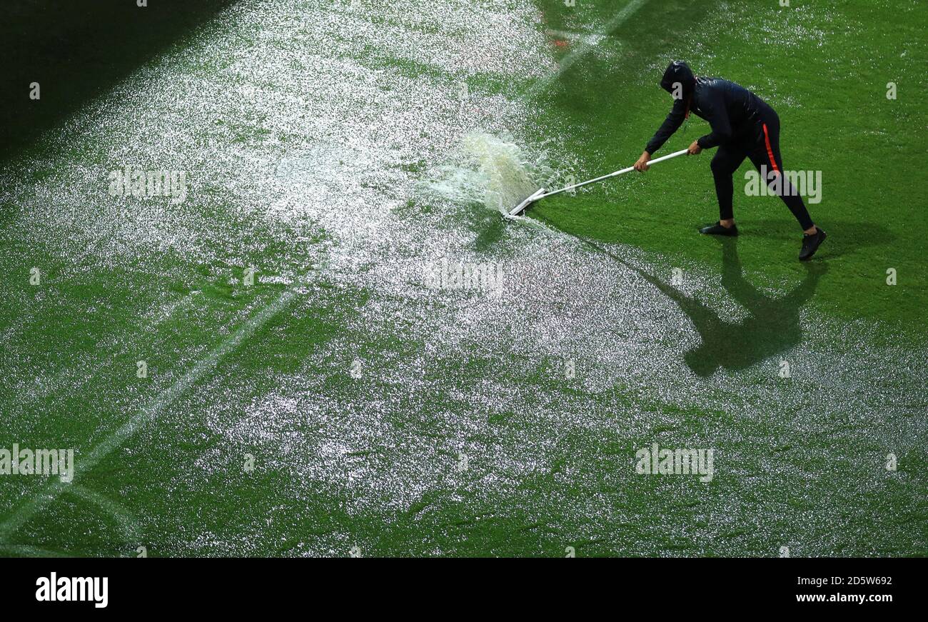 Groundstaff sweep water off the pitch as heavy rain delays kick off
