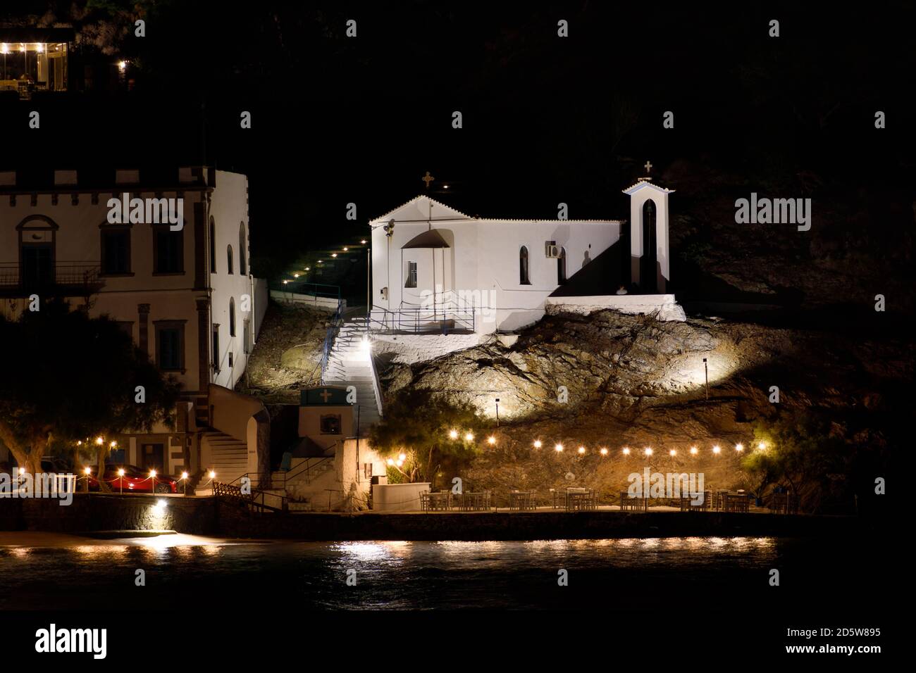 The church of Santa Paraskevi on the rock in front of the sea, with taverns and houses, on the island of Lemnos in Greece Stock Photo