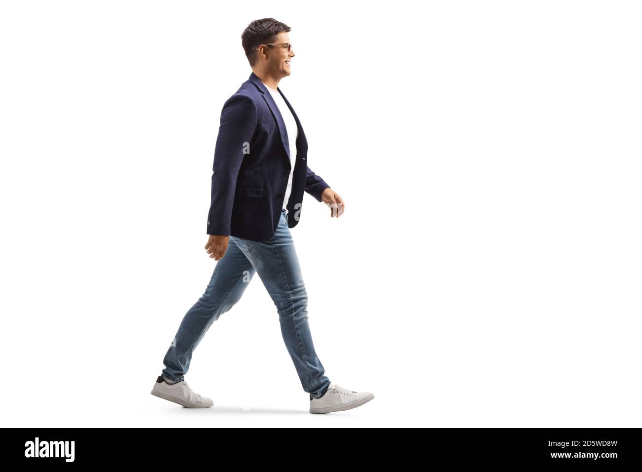 Full length profile shot of a smiling young man in jeans and suit walking isolated on white background Stock Photo