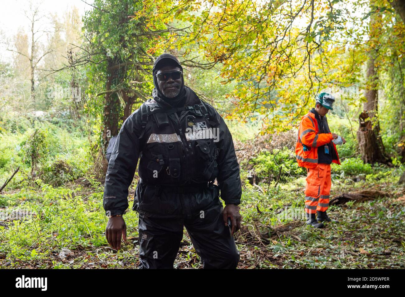 Denham, Buckinghamshire, UK. 14th October, 2020. An Enforcement Agent without a name or number on his jacket from the the National Eviction Team in Denham Country Park stops members of the public and press from standing on a public footpath next to an area where HS2 have been felling a large of mature trees. NET Enforcement Agents continue to record footage of members of the press and the public for 'profiling' reasons. Credit: Maureen McLean/Alamy Live News Stock Photo