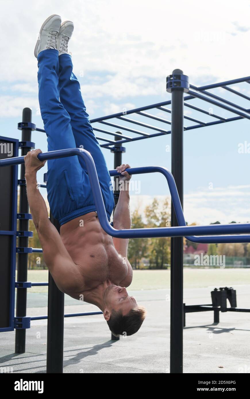 Active toned man workout on parallel bars outdoors. Active lifestyle ...