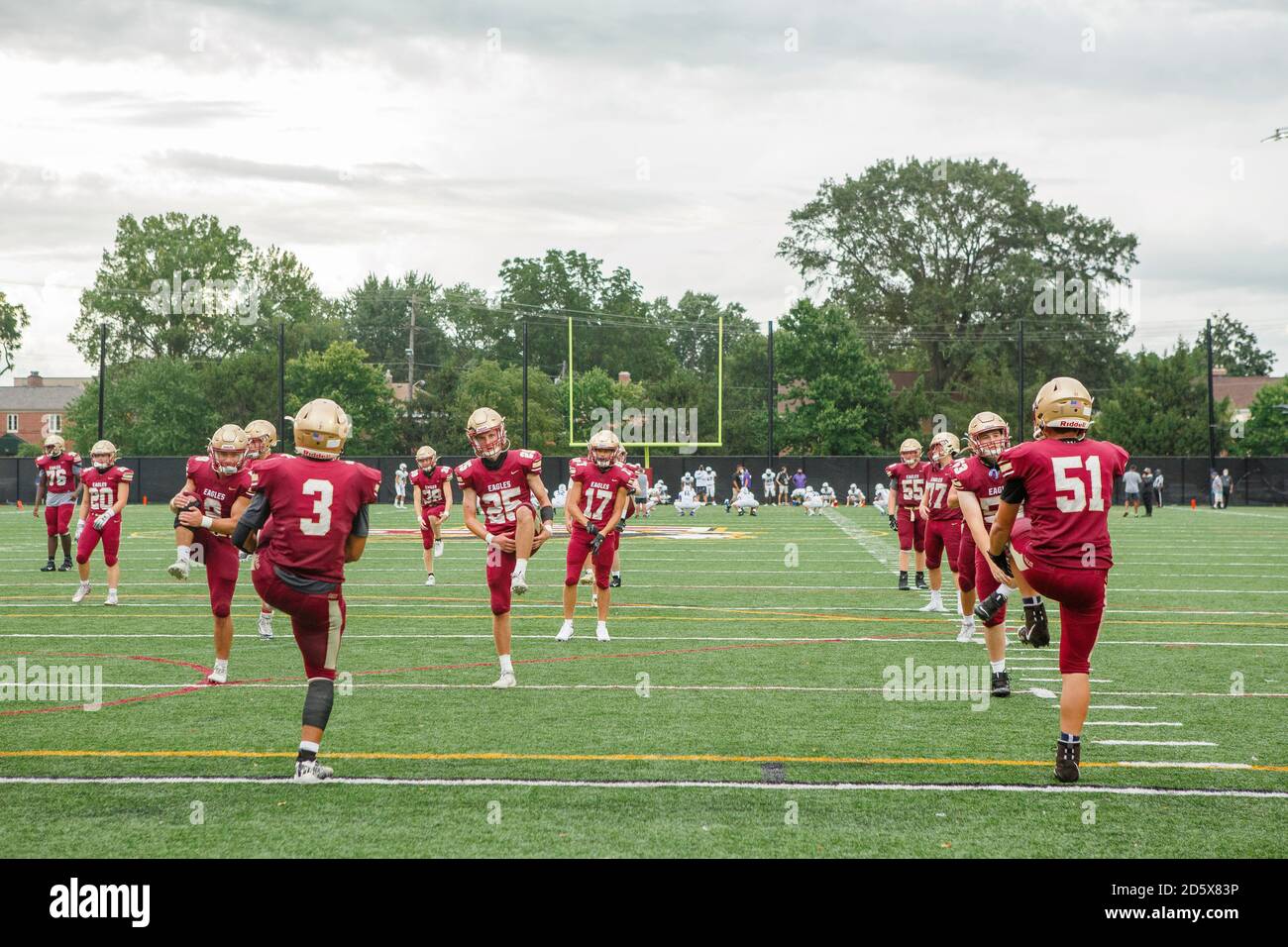 a team of high school players warm up on a football field in uniform Stock Photo