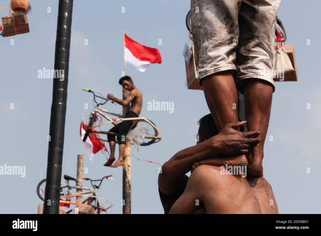 Men climbing poles to win prizes at the Indonesian Independence Day celebrations, Jakarta. Stock Photo