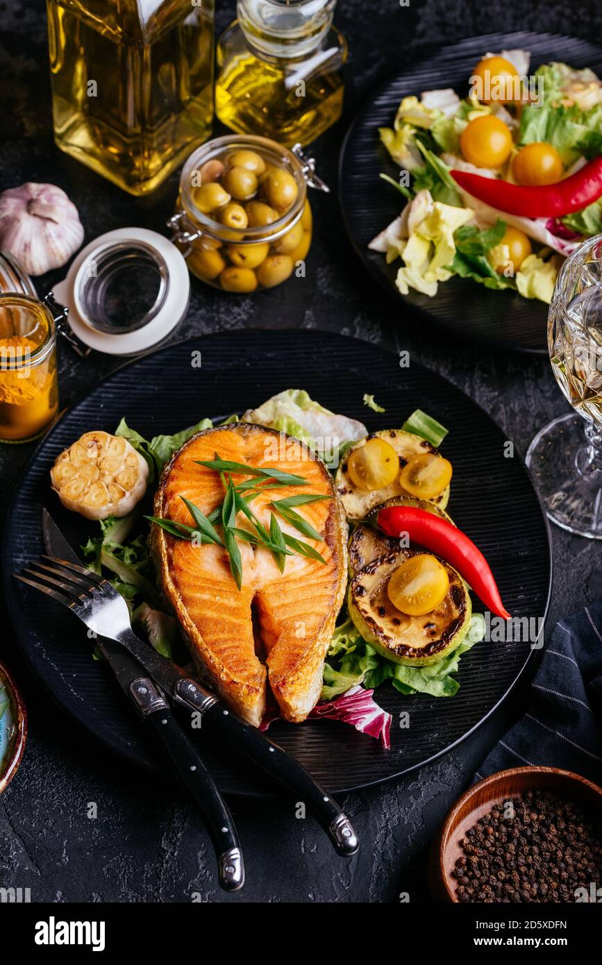 salmon steak baked on coals with vegetables on a black background Stock ...