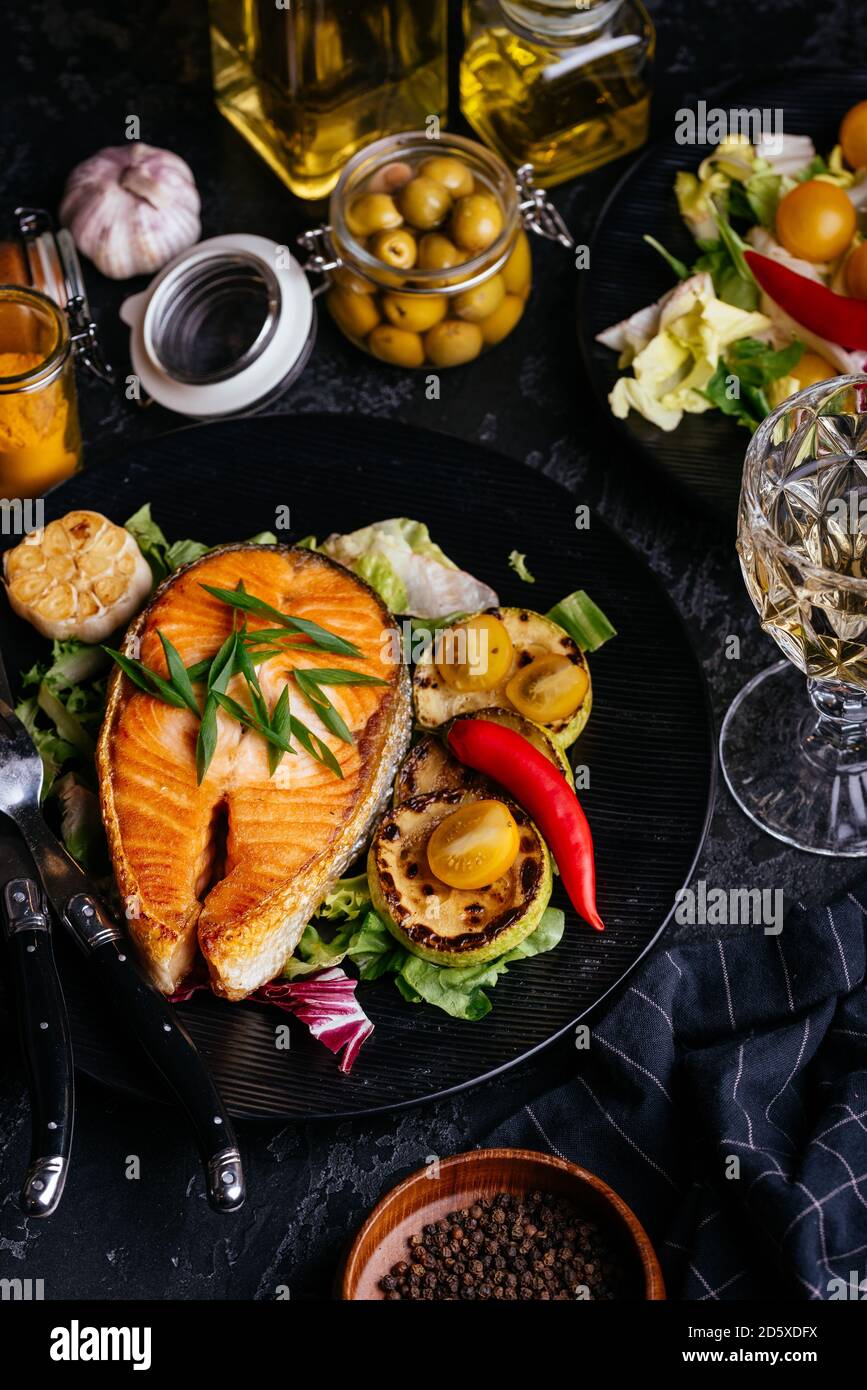 salmon steak baked on coals with vegetables on a black background Stock ...