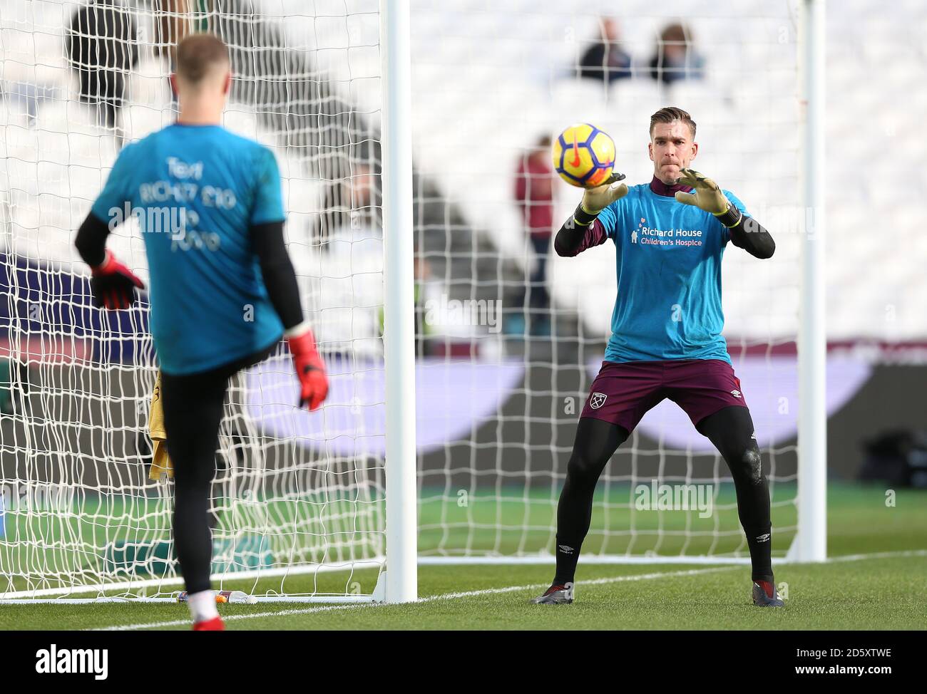 West Ham United goalkeeper Joe Hart (left) kicks the ball to team-mate Adrian during pre-match training Stock Photo