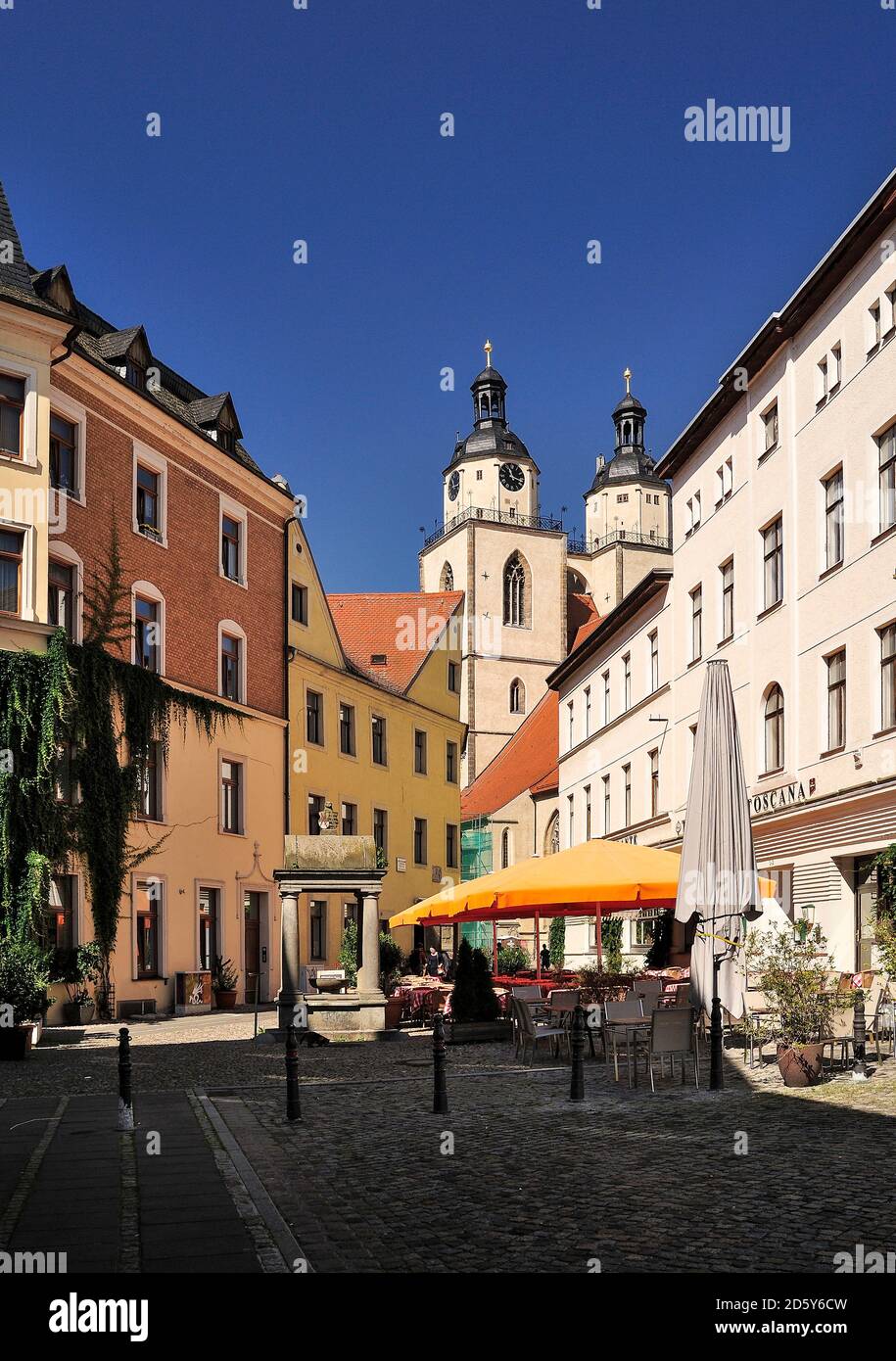 Germany, Lutherstadt Wittenberg, view to sidewalk cafe, houses and St Mary's Church in the background Stock Photo