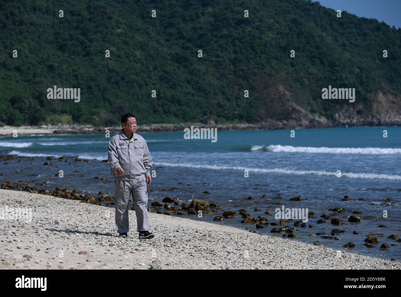 (201014) -- SHENZHEN, Oct. 14, 2020 (Xinhua) -- Qiao Sukai walks on the beach in Shenzhen, south China's Guangdong Province, Nov. 20, 2019. Every 18 months, the Dayawan Nuclear Power Plant has to undergo a fuel assemblies replacement, which is one of the most important moments for the nuclear power plant. Dozens of engineers are divided into four shifts and operate the equipment day and night when the reactor is shut down. Their leader, Qiao Sukai, has been dealing with nuclear fuel since July 1993 when the nuclear fuel assembly of Dayawan Nuclear Power Plant arrived.    The professional and t Stock Photo