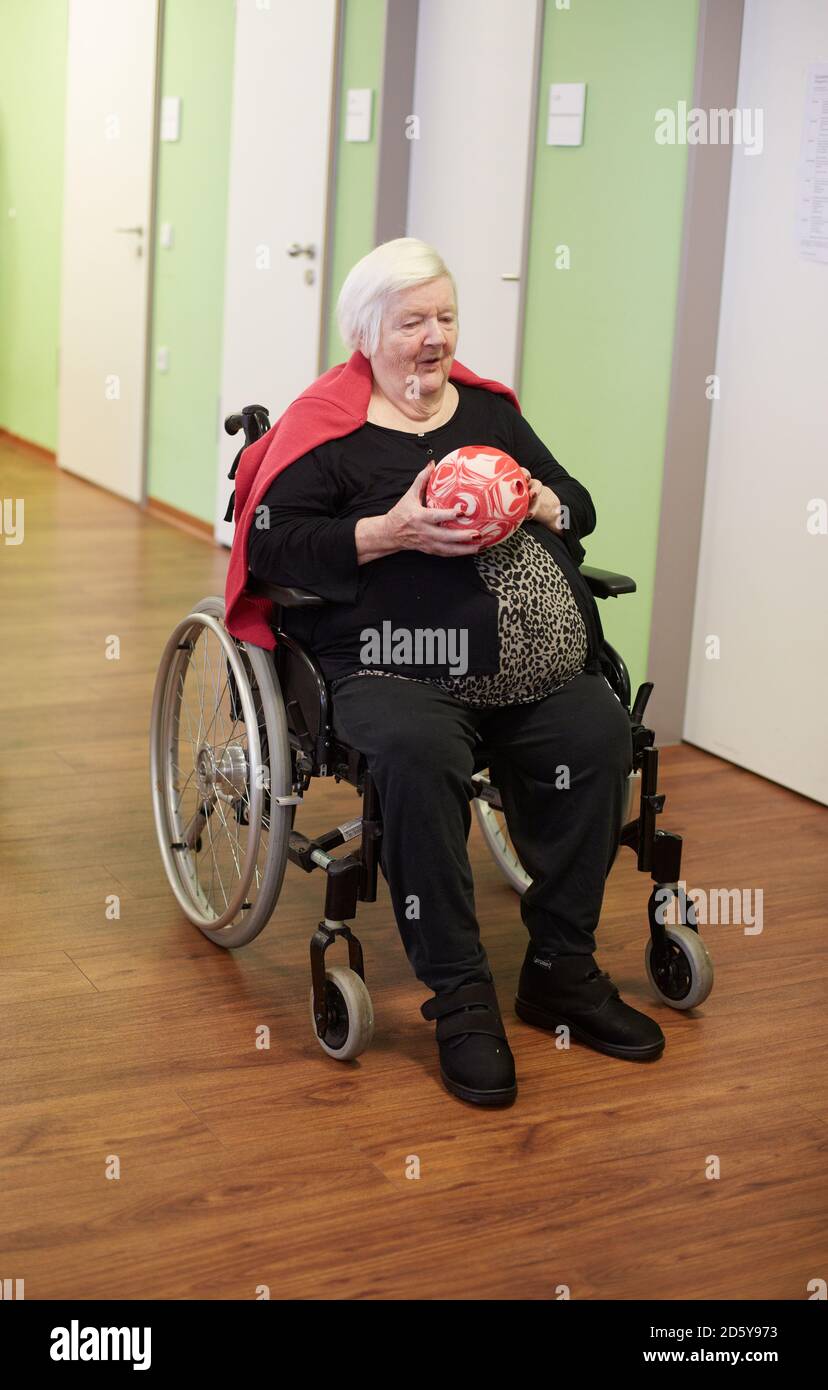 Age demented senior woman bowling with foam ball in a nursing home