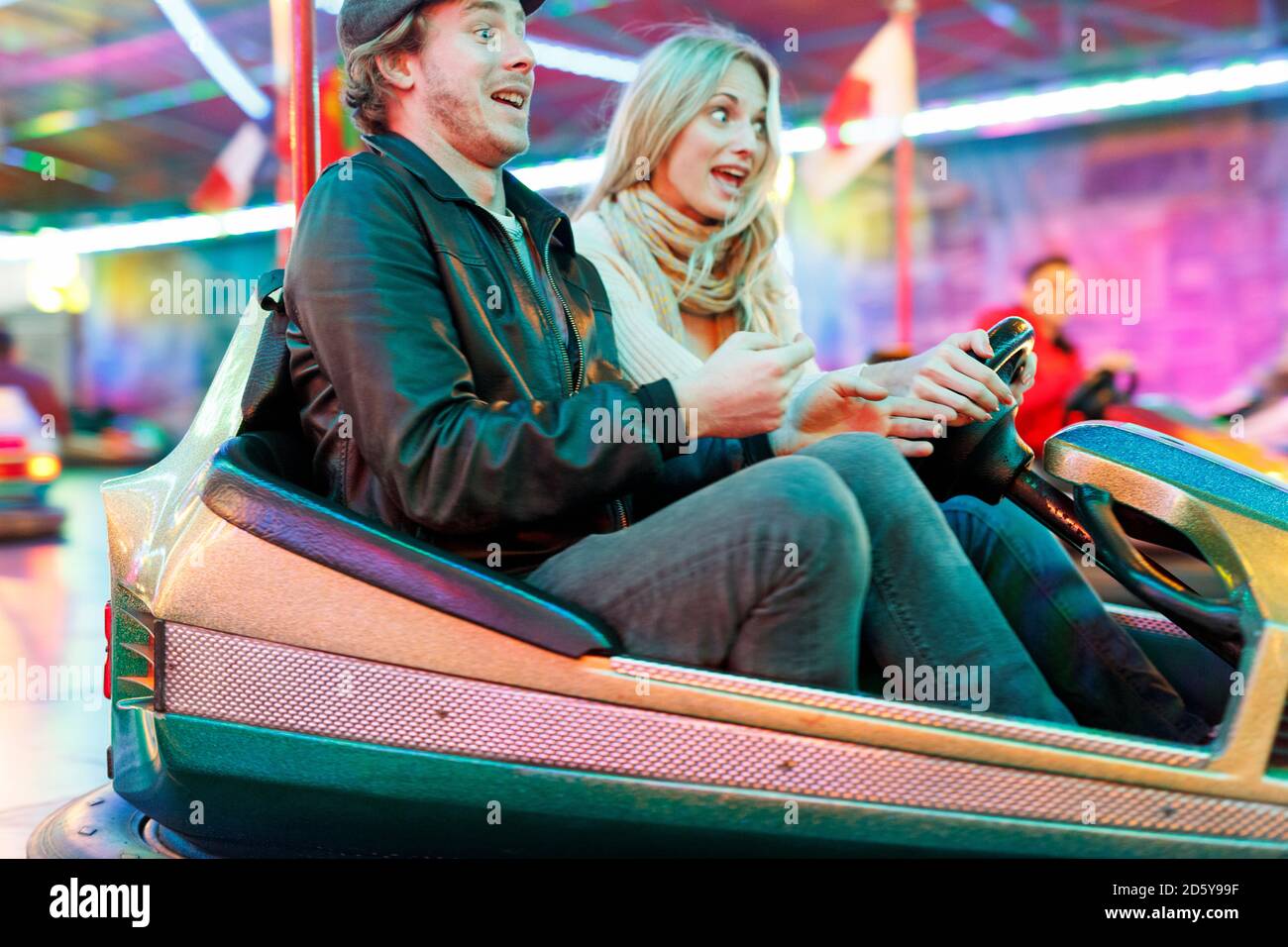 Young couple at fun fair riding bumper car Stock Photo