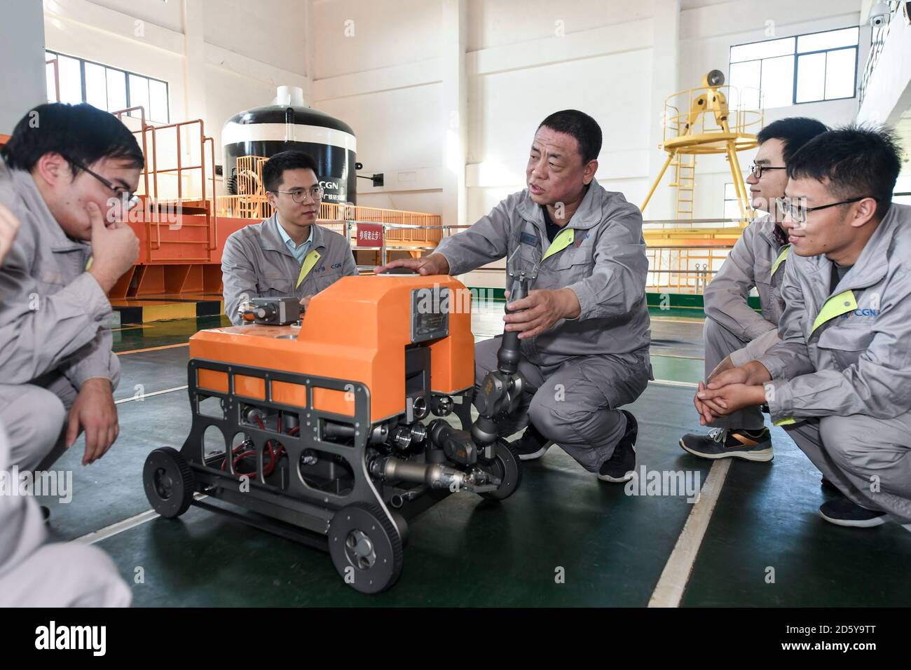 (201014) -- SHENZHEN, Oct. 14, 2020 (Xinhua) -- Qiao Sukai (C) discusses with his team members on an underwater robot at a training center in Shenzhen, south China's Guangdong Province, Nov. 20, 2019. Every 18 months, the Dayawan Nuclear Power Plant has to undergo a fuel assemblies replacement, which is one of the most important moments for the nuclear power plant. Dozens of engineers are divided into four shifts and operate the equipment day and night when the reactor is shut down. Their leader, Qiao Sukai, has been dealing with nuclear fuel since July 1993 when the nuclear fuel assembly of D Stock Photo