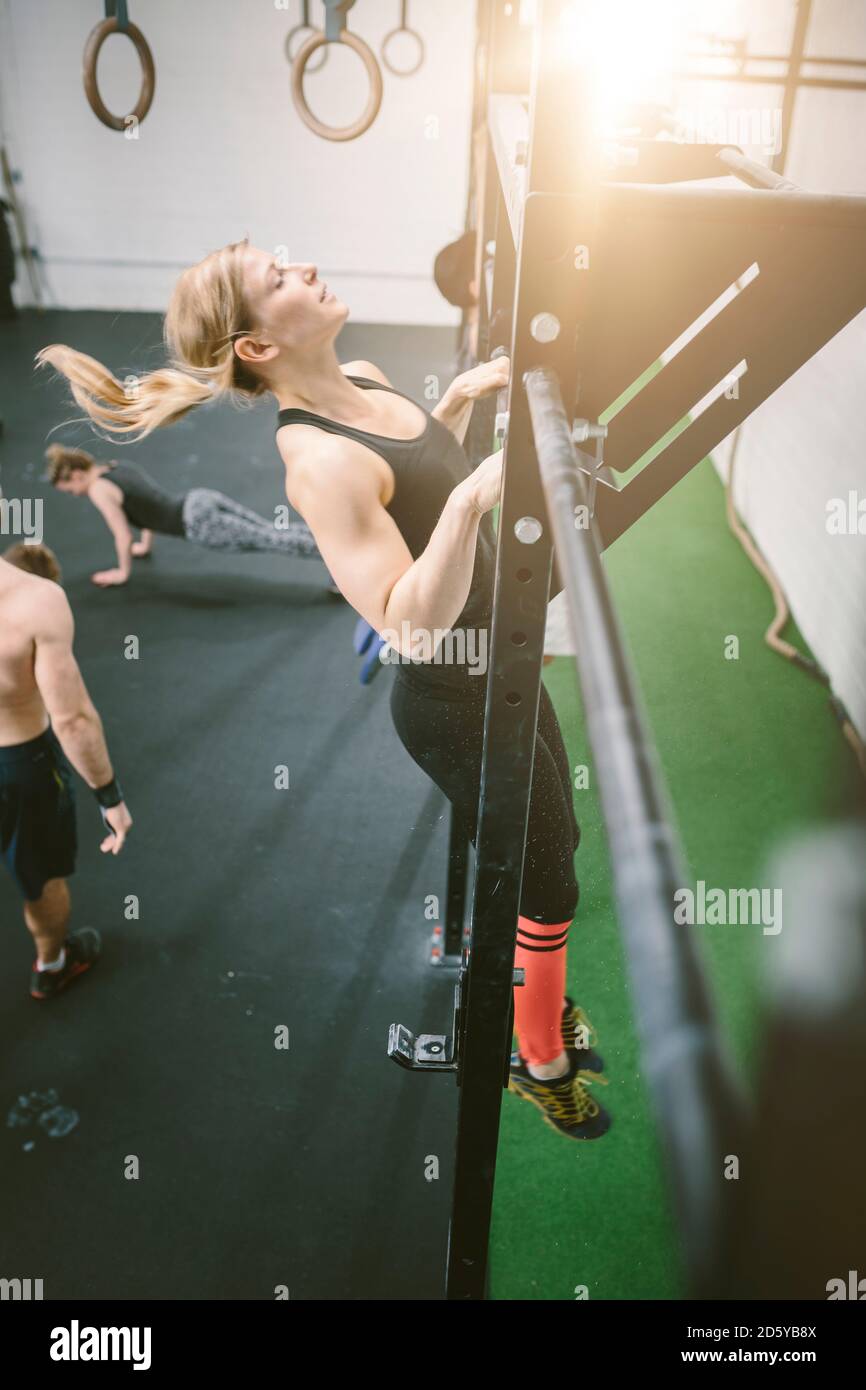 Woman in gym doing chin ups Stock Photo