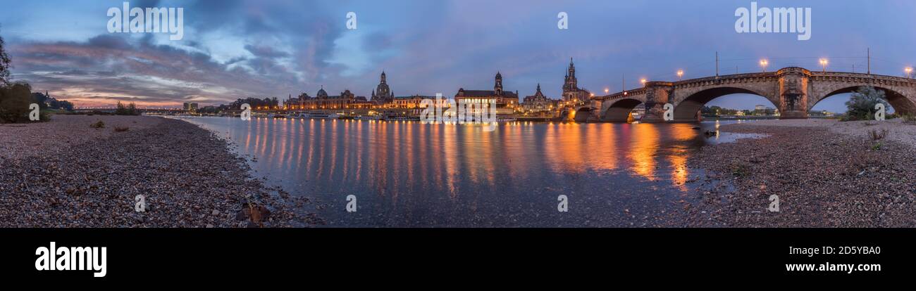Germany, Dresden, view to lighted Old city with riverside of Elbe River in the foreground at morning twilight Stock Photo