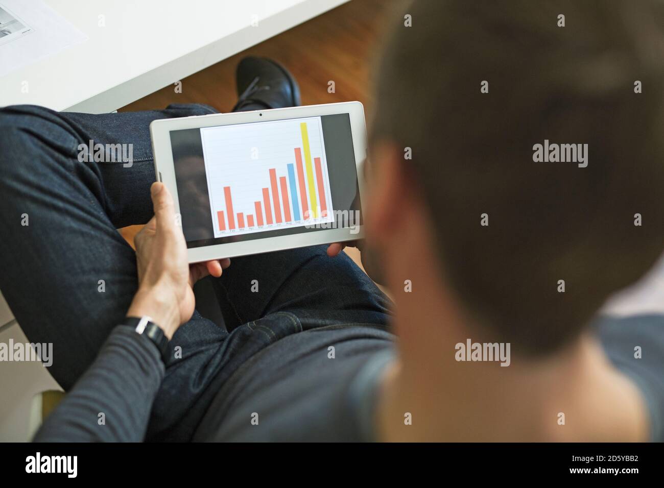 Businessman analyzing bar chart on tablet in office Stock Photo