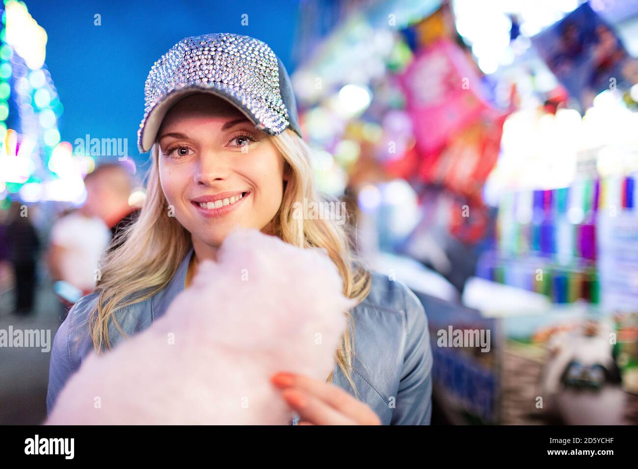 Young woman at fun fair eating candy floss Stock Photo