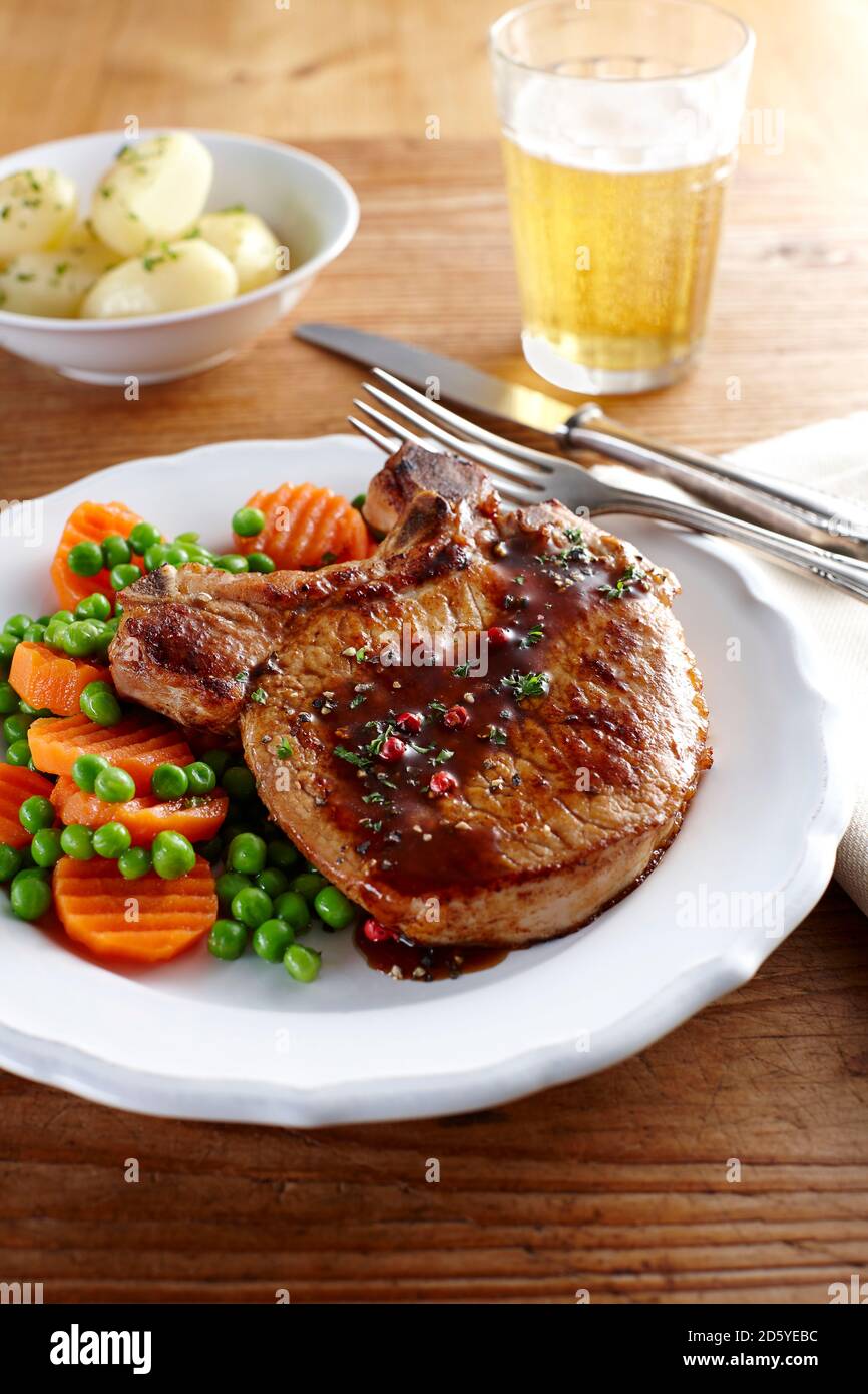 Pork chop with carrots, peas and boiled potatoes on plate Stock Photo