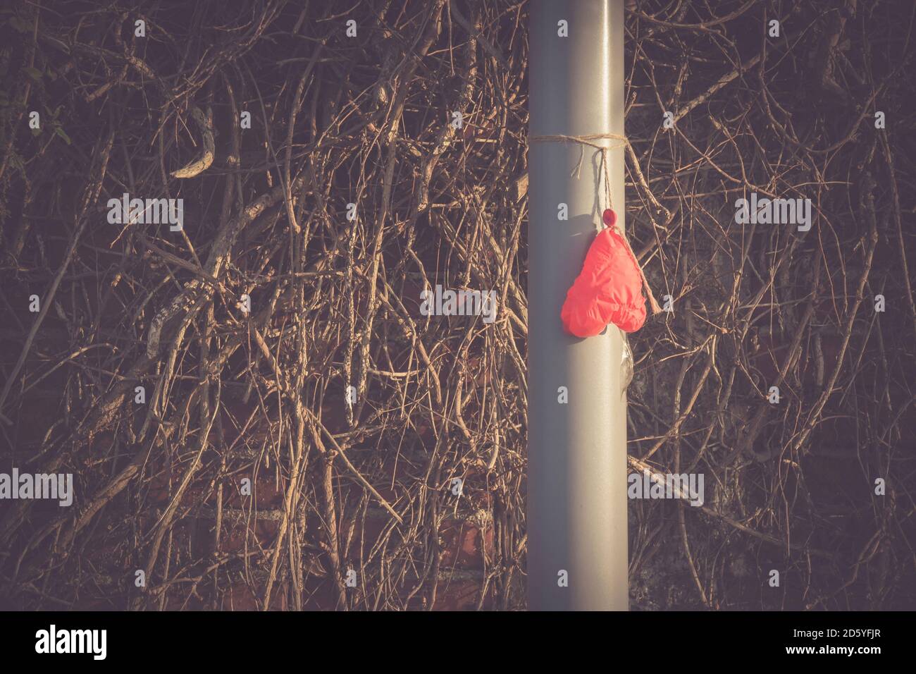 Deflated heart-shaped balloon hanging on a pole Stock Photo