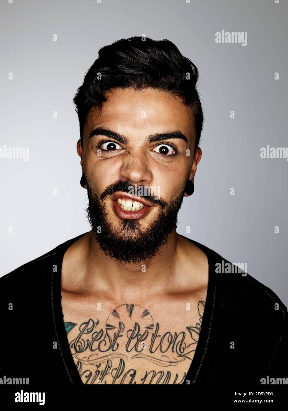 Portrait of angry man with tatoo on his chest Stock Photo