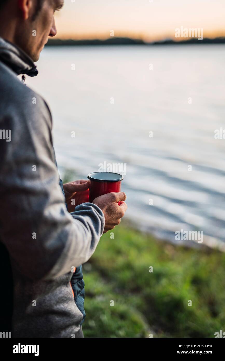Man looking at the lake, drinking coffee Stock Photo