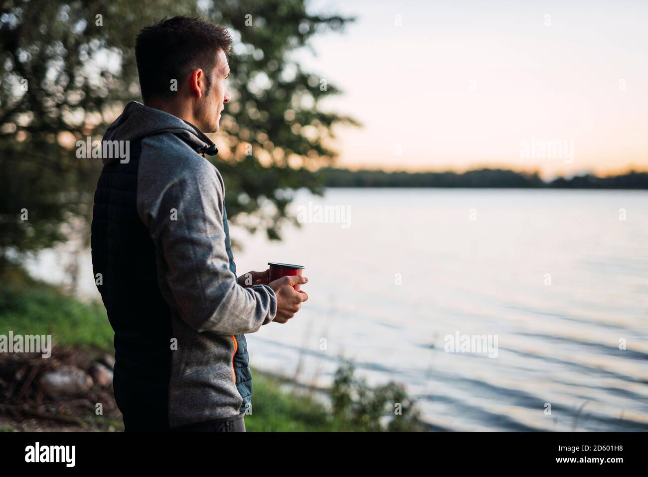 Man looking at the lake, drinking coffee Stock Photo