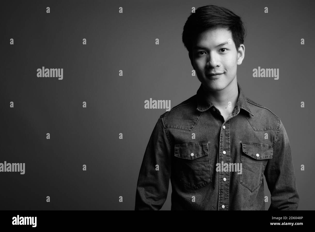 Young handsome Asian man wearing denim shirt against gray background Stock Photo