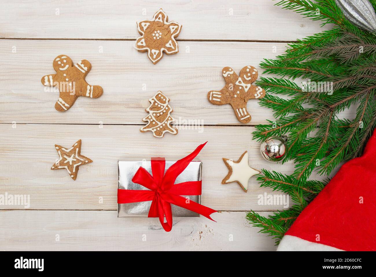 Two gift boxes with red ribbons on a light wooden background,ginger shaped cookies and Christmas tree branches. Concept of New Year and Christmas, gif Stock Photo