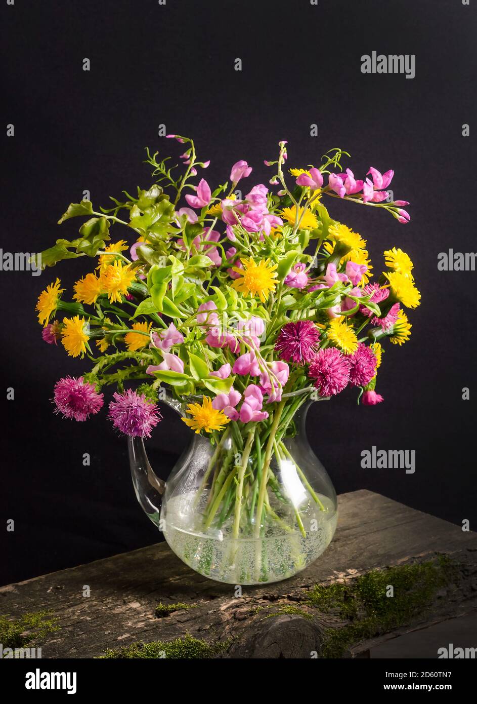 Lush bouquet of wild flowers in a vase on a black background in dark ...