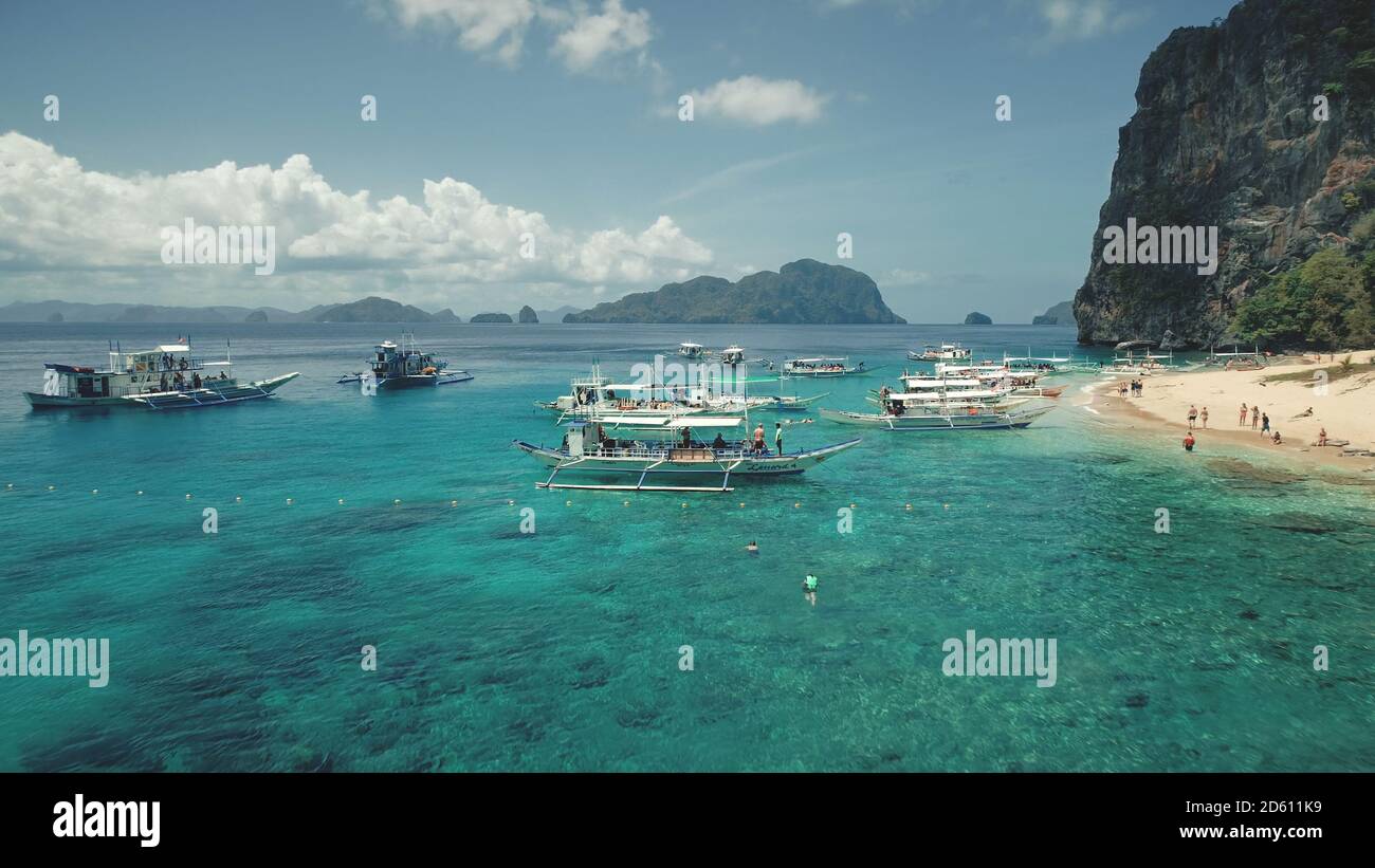 Ocean sand coast with vessels aerial timelapse. Boats and ship at shallow azure water. People rest on sandy beach. Asia tourist landmark on Palawan island, El Nido, Philippines, Asia Stock Photo