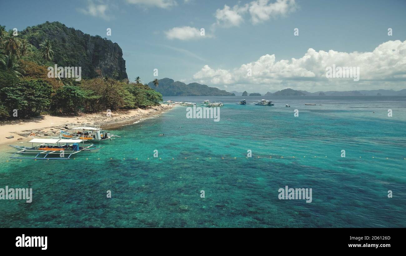 Aerial view of sea bay coast turquoise water with transport: passenger boats, vessels at sand beach. Amazing tropical seascape at Palawan Island, Philippines archipelago, Asia. Cinematic drone shot Stock Photo