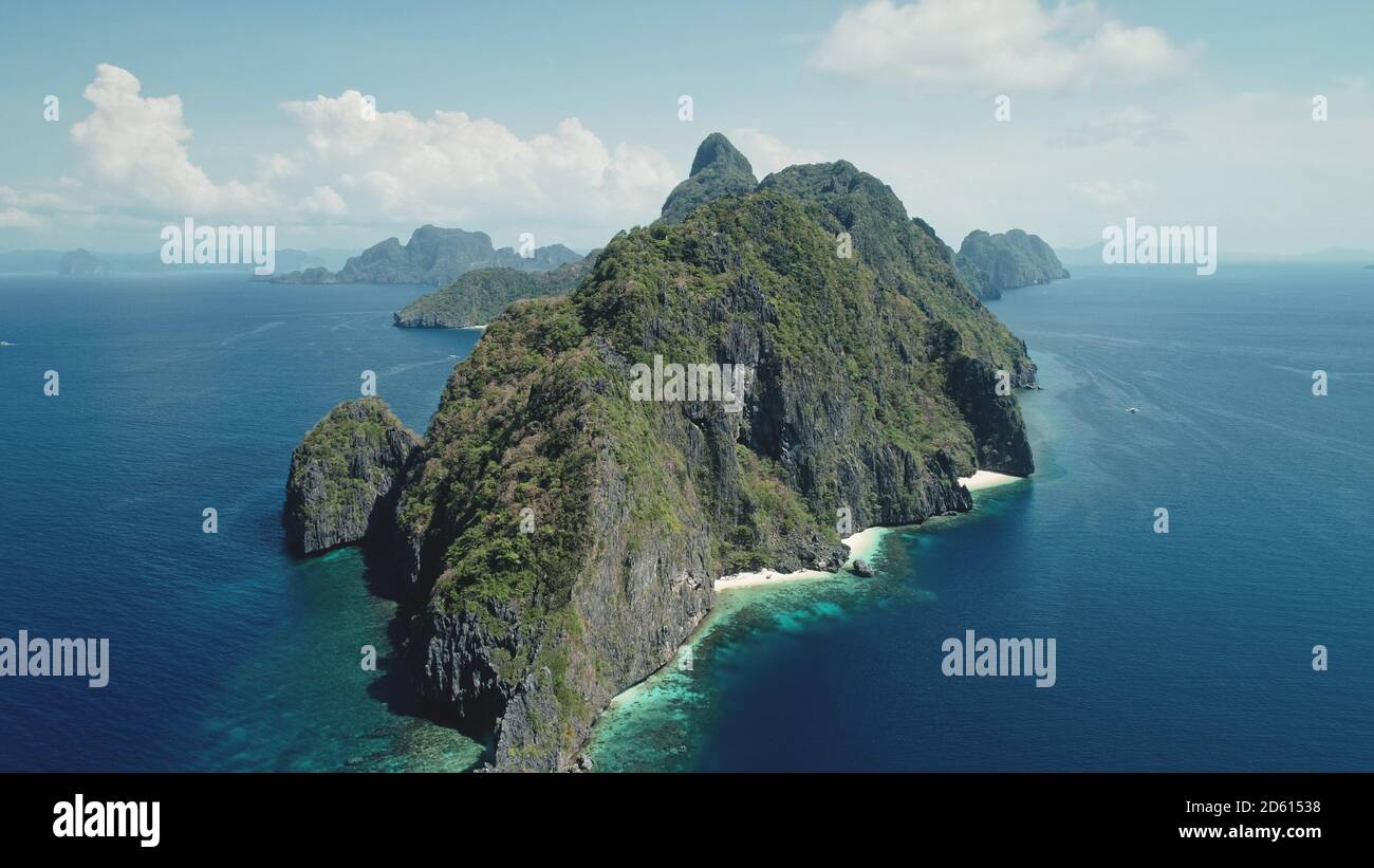 Hilly island at ocean gulf drone view. Green trees, plants at mountain rocks at paradise isle. Wonderful landscape of El Nido islet, Philippine, Visayas. Cinematic summer scenery aerial birds-eye shot Stock Photo