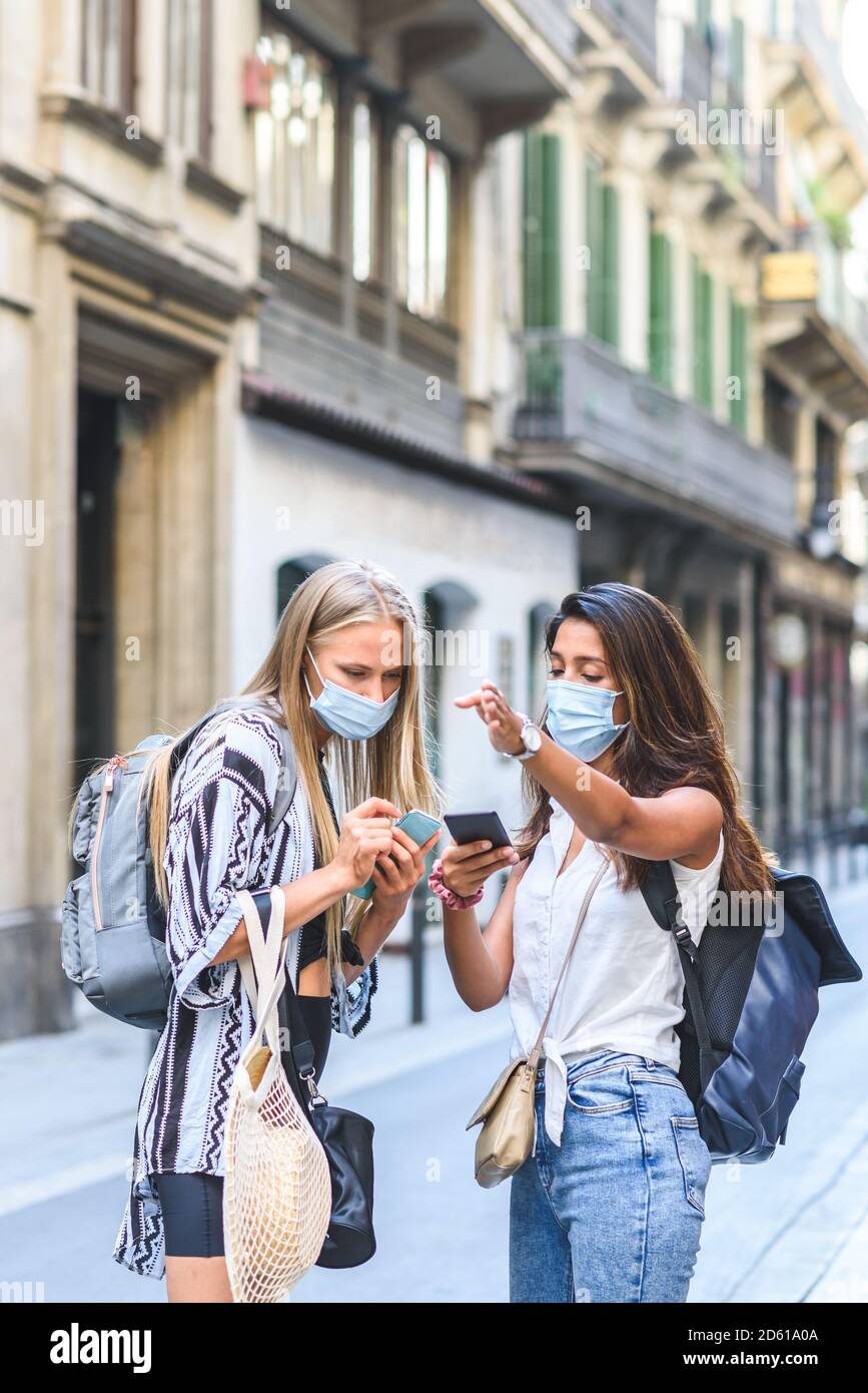 young indian female tourist helping other caucasian tourist to find an address with the help of an smart phone Stock Photo