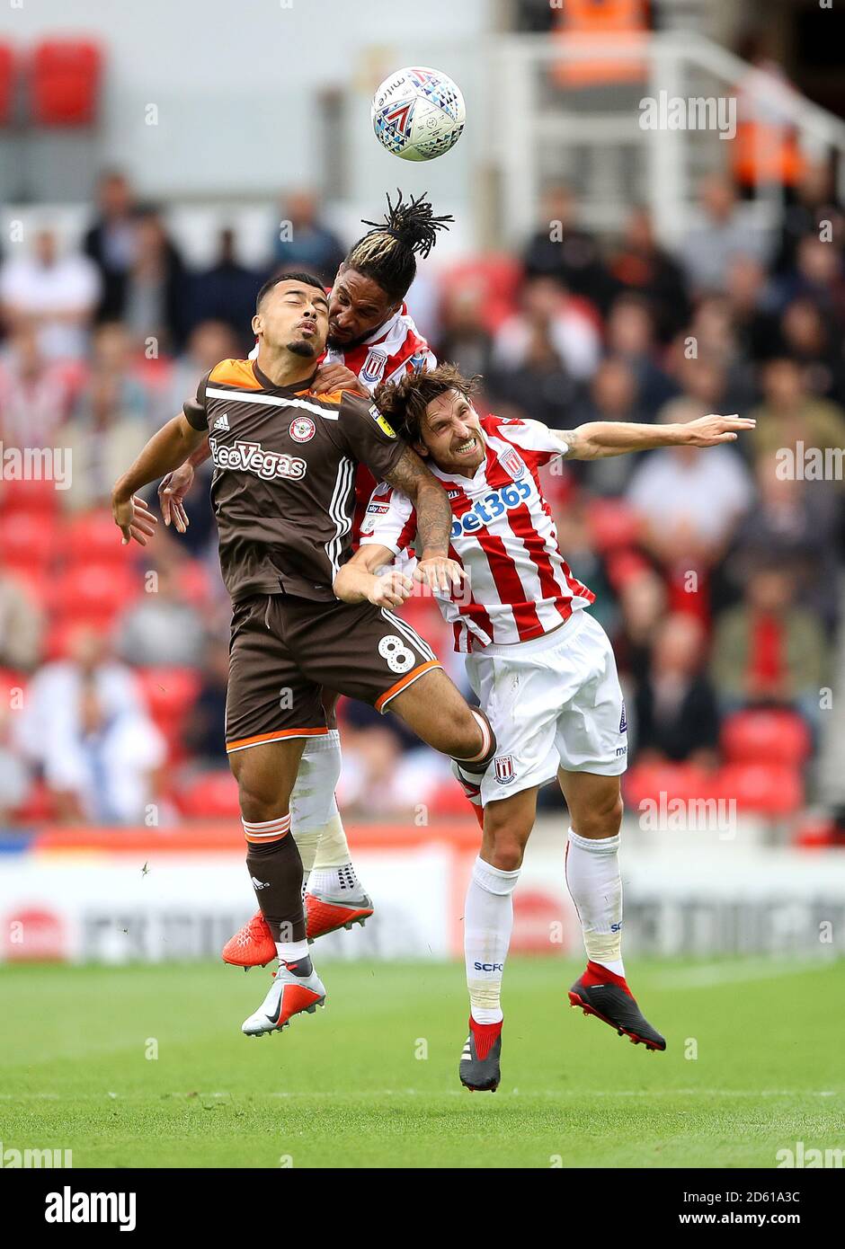Brentford's Nico Yennaris (left) battles for the ball in the air with Stoke City's Ashley Williams (centre) and Joe Allen (right) Stock Photo
