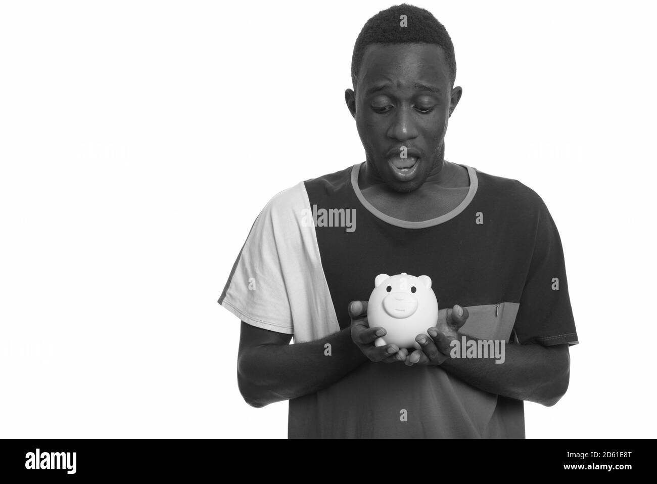 Young African man holding piggy bank looking shocked Stock Photo - Alamy