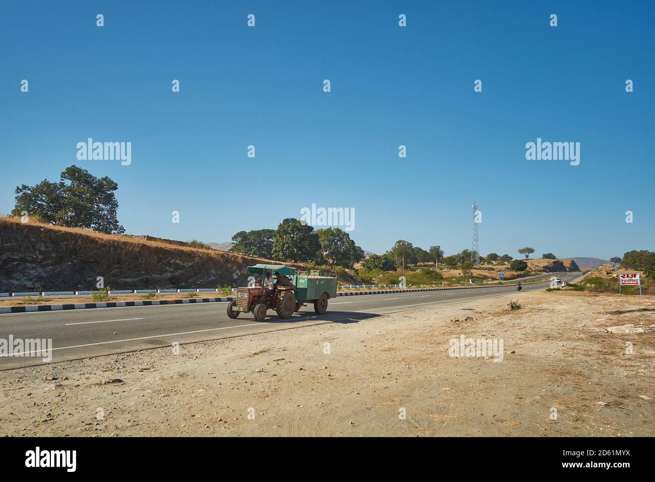 A farm tractor pulling a trolley of farm produce towards the markets