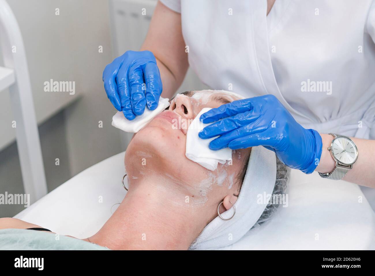 The young female client of cosmetic salon having a face cleaning procedure. The doctor cosmetologist cleaning skin with sponge. Concepts of skin care Stock Photo