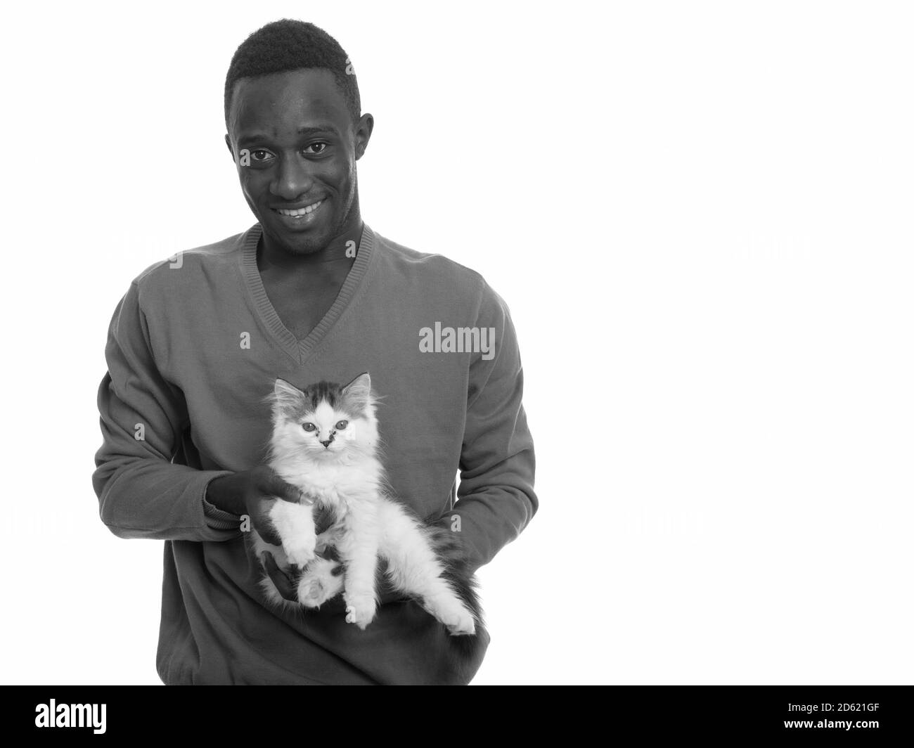 Young happy African man smiling and holding cute cat Stock Photo