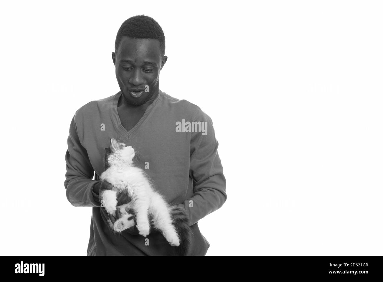 Young African man making funny face while holding cute cat Stock Photo