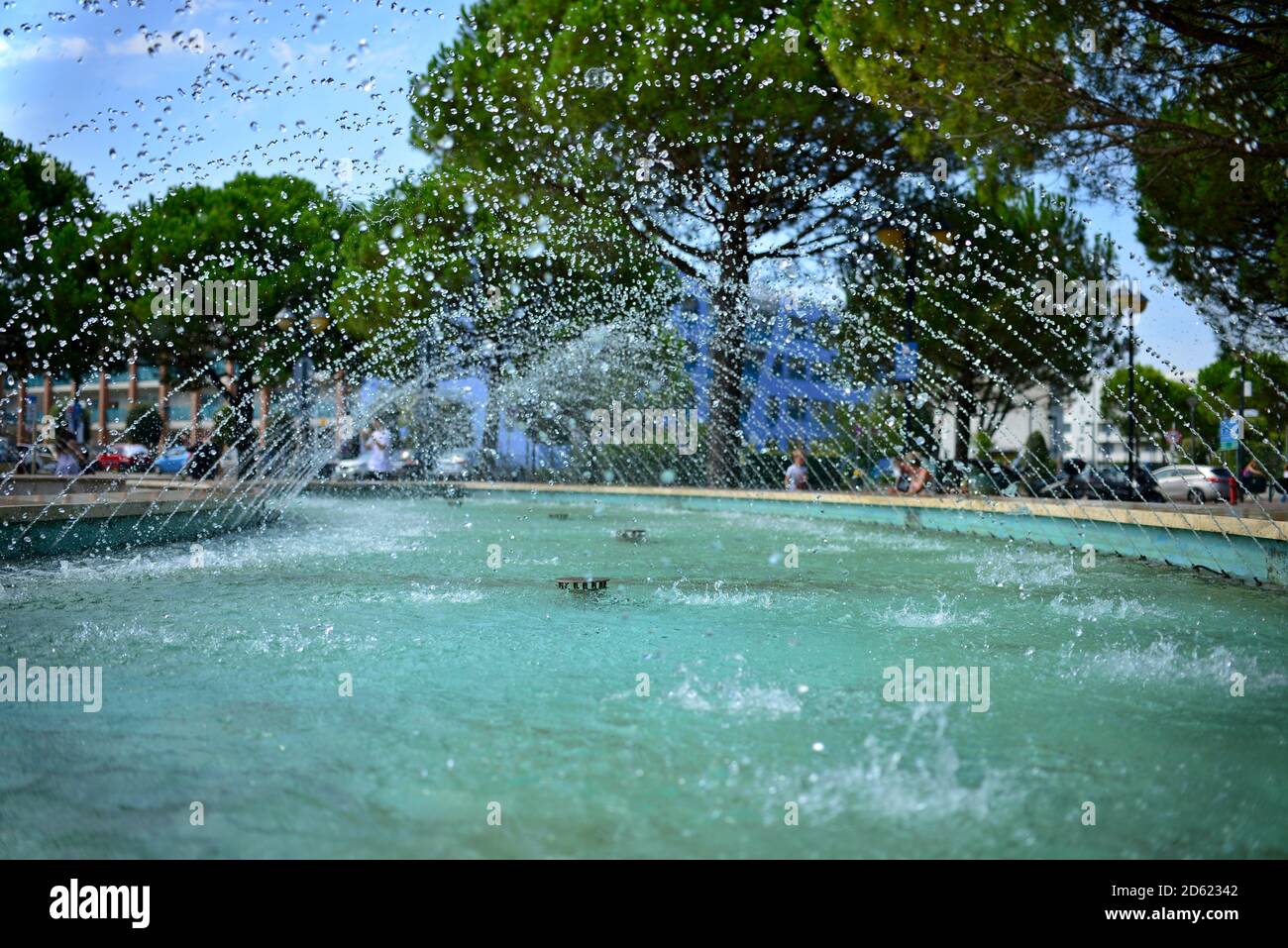 View of tiny drops of water gushing from a fountain. Blue water surface and many small drops of flying water. View into the stream inside the fountain Stock Photo