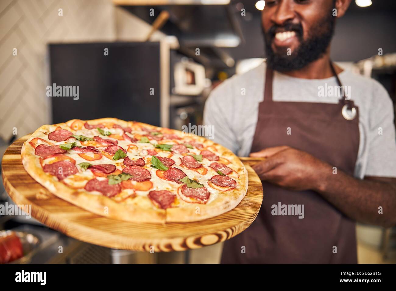 Joyful Afro American young man holding pepperoni pizza Stock Photo